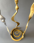 Forged steel Baby Bloom sculpture showing circular freestanding base with hand forged spiral detail and gold metallic finish.