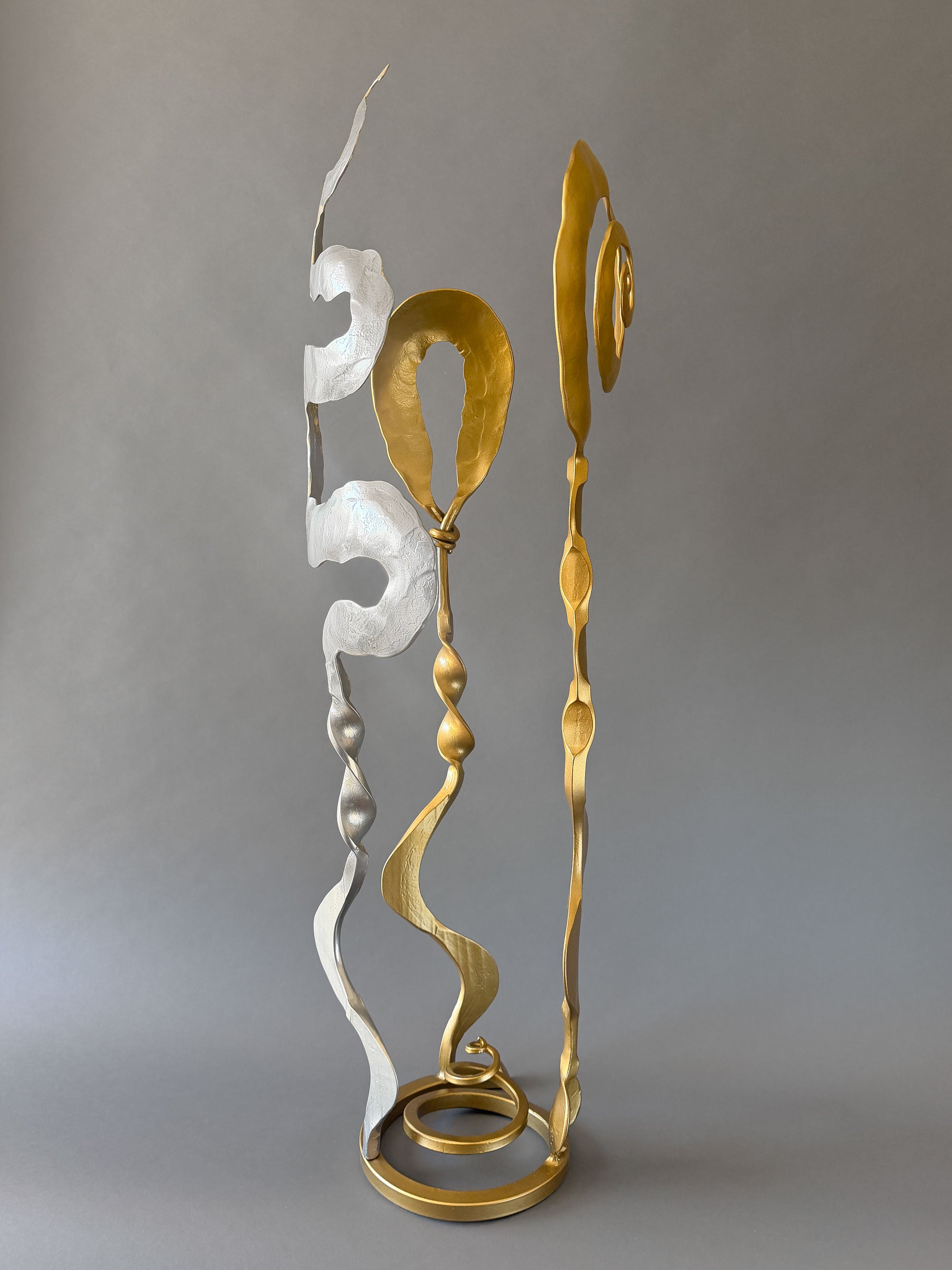 Gold and chrome Baby Bloom steel sculpture by Christopher Thomson with spiral top and flowing forged elements on a freestanding circular base.