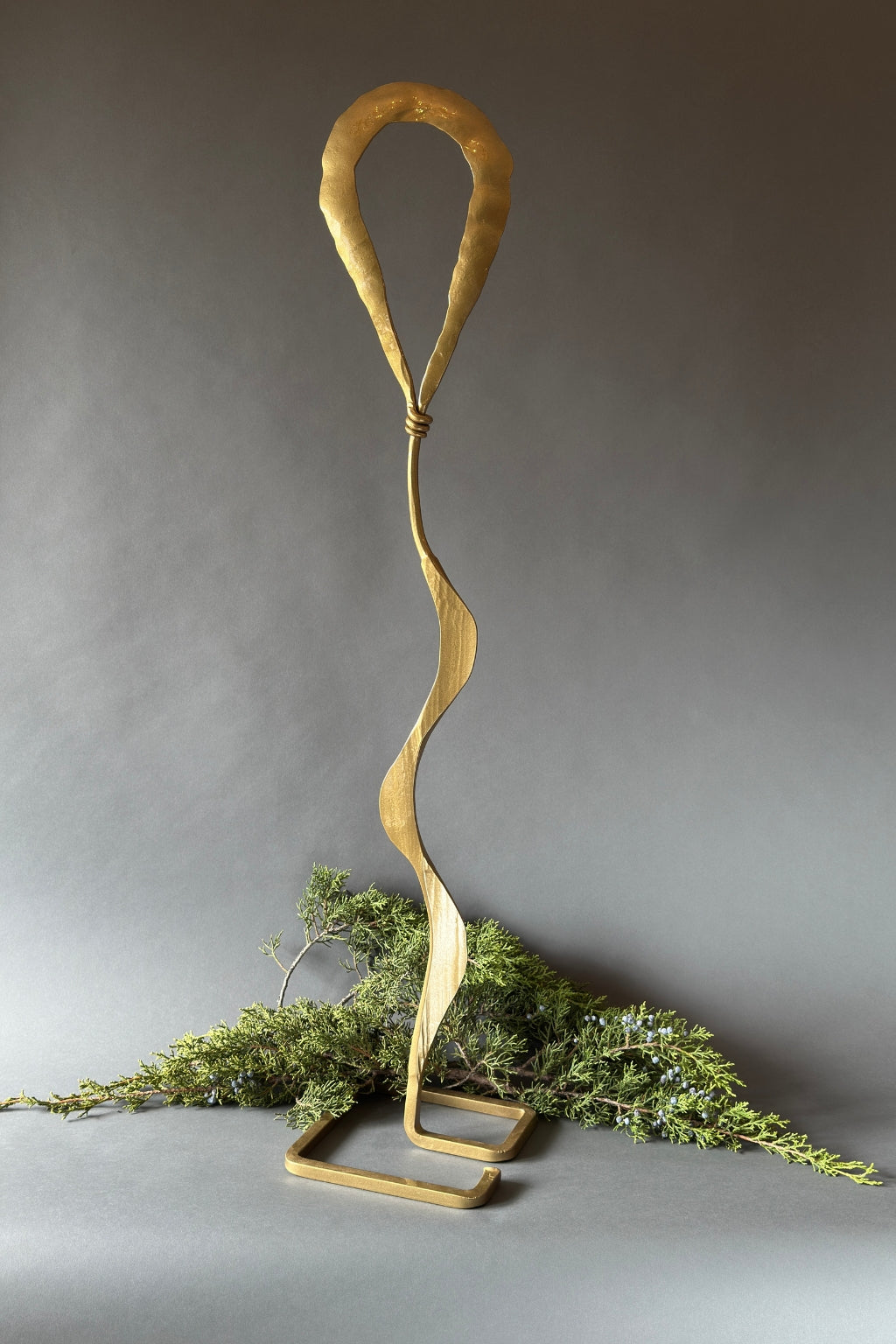Gold metal sculpture with wavy design on a gray background