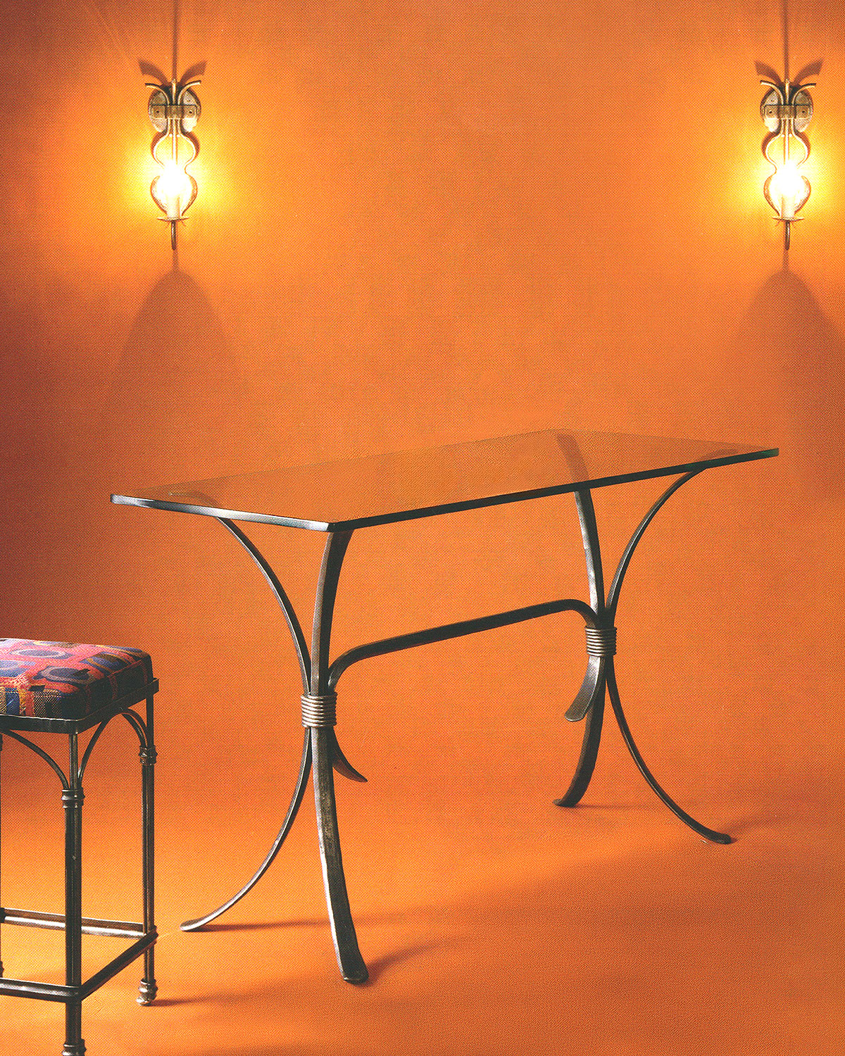  Wrought iron martini bar table base with curved legs joined by wrapped collars, shown with a clear glass top on an orange backdrop