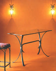  Wrought iron martini bar table base with curved legs joined by wrapped collars, shown with a clear glass top on an orange backdrop