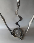 Close-up view of the lower portion of a metallic steel Baby Bloom sculpture showing the forged spiral base and three sculptural stems.
