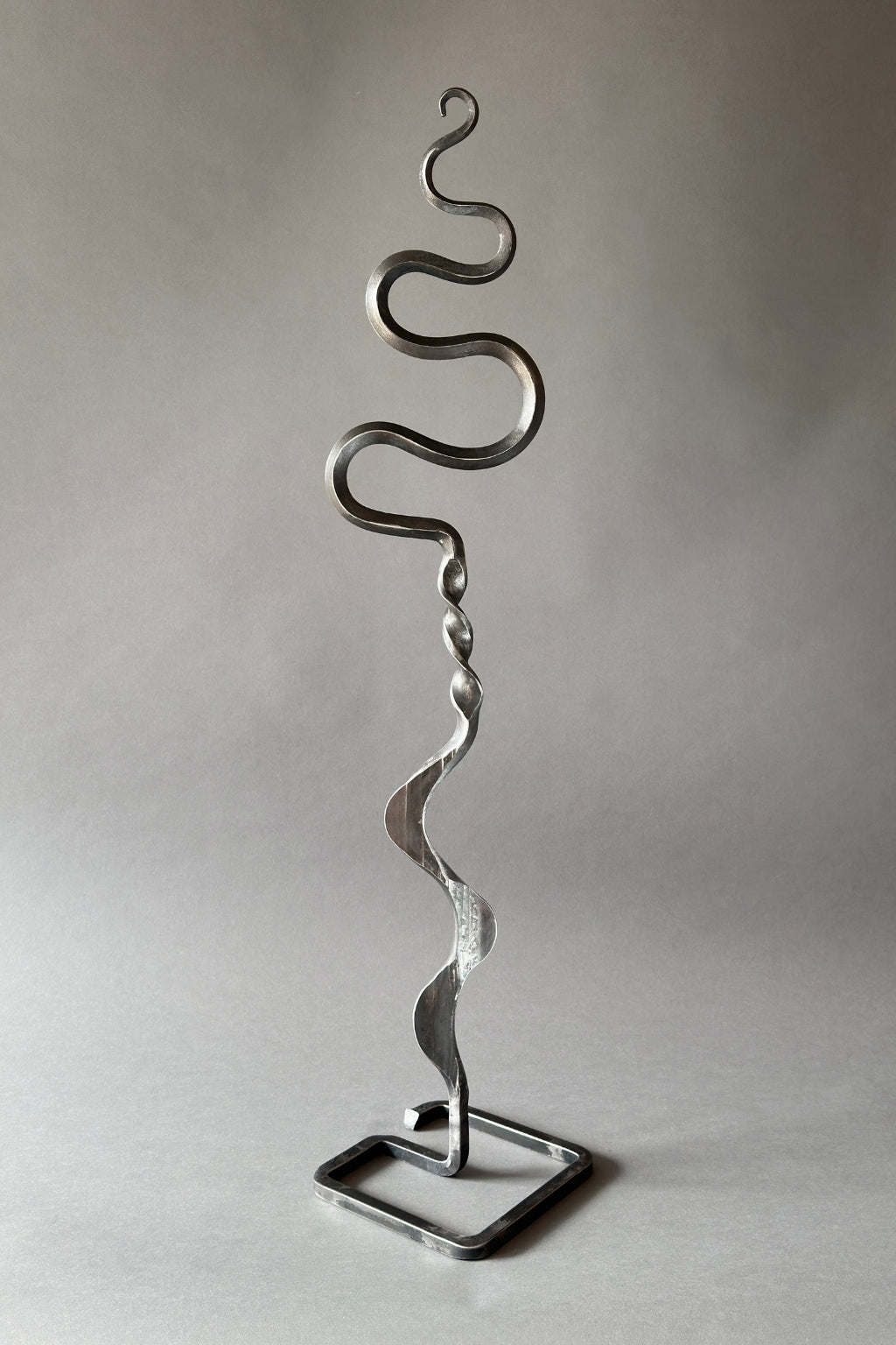 Metallic sculpture with wavy design on a plain background