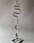 Metallic sculpture with wavy design on a plain background