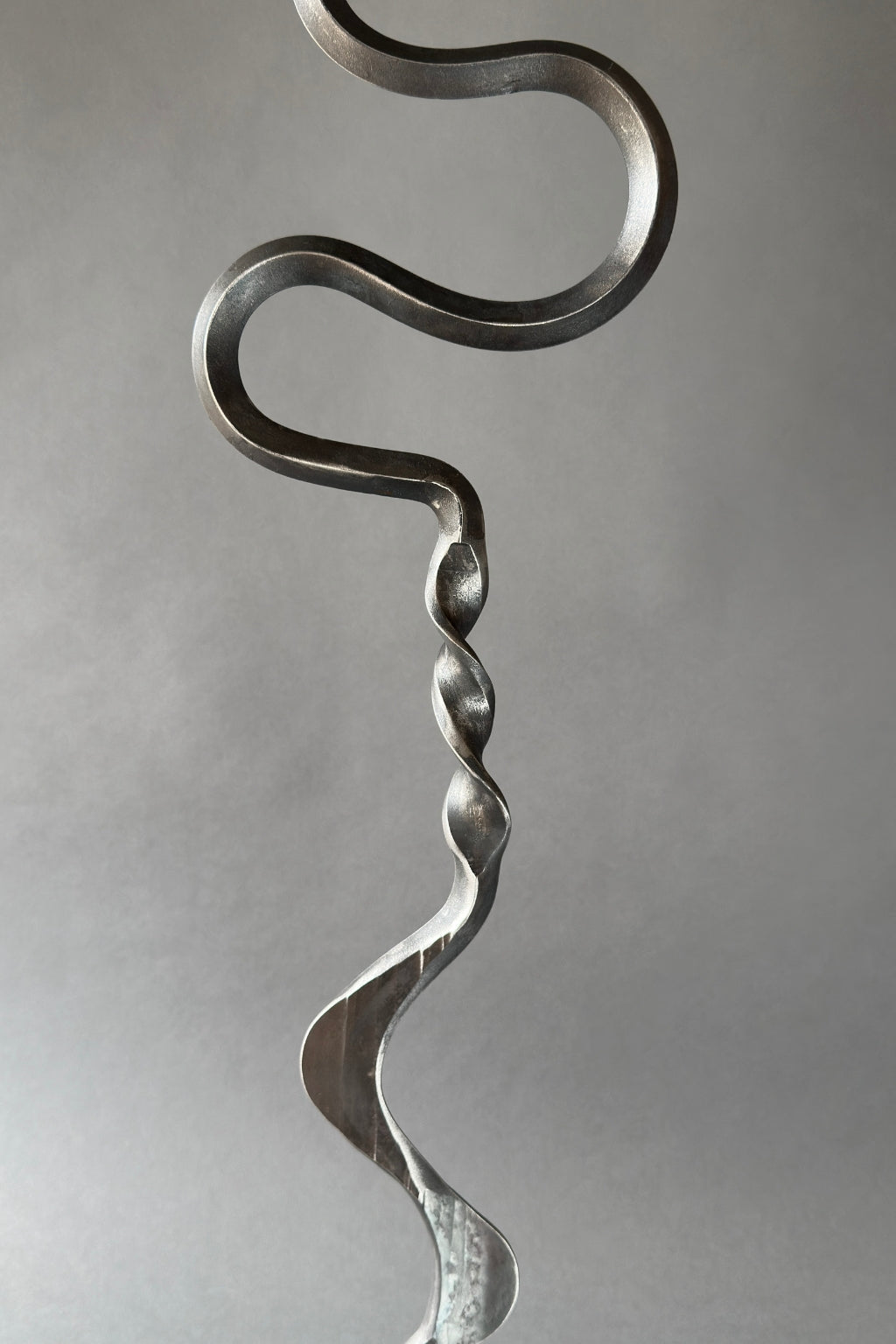 Metallic sculpture of a wavy, abstract design on a gray background