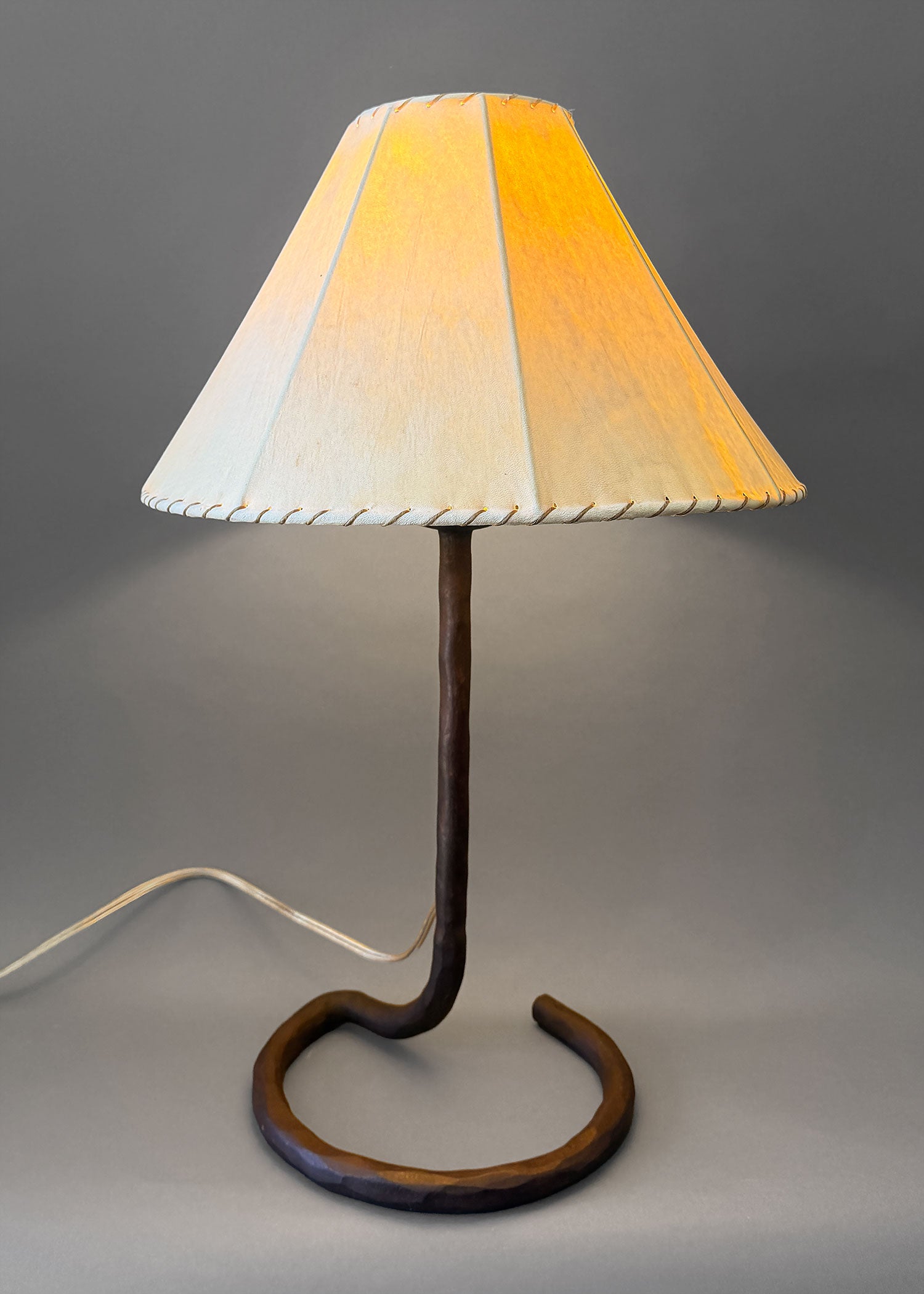 Wrought iron hand forged bedside lamp with a unique circle base and a sheepskin shade.