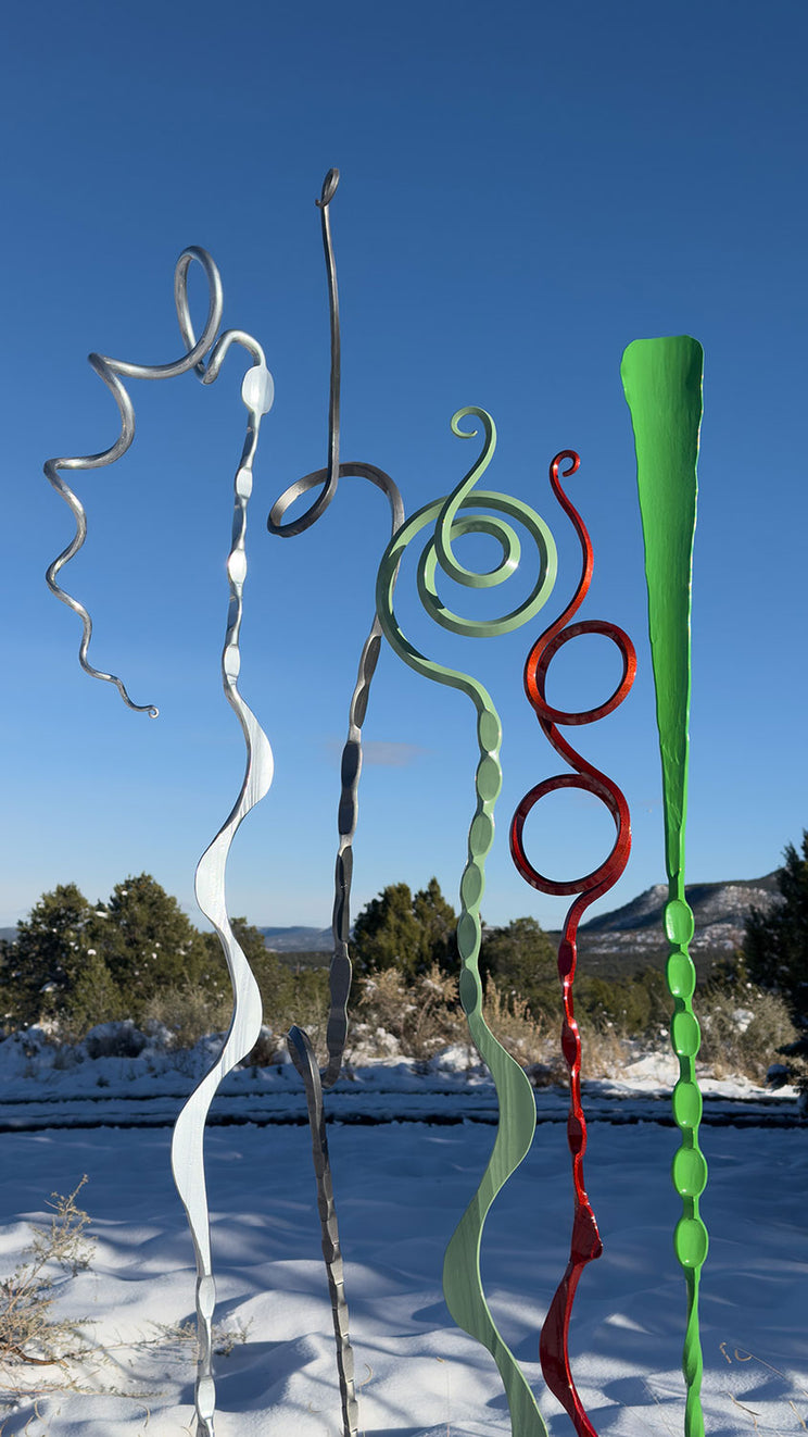 Abstract steel sculptures in a snowy scene. The colorful unique sculptures are in a variety of Christmas colors.