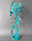 Turquoise metal sculpture with swirling design on a gray background