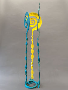 Turquoise and Yellow small sculpture that has two turquoise elements and one yellow element. All three elements are welded onto a spiral turquoise base,