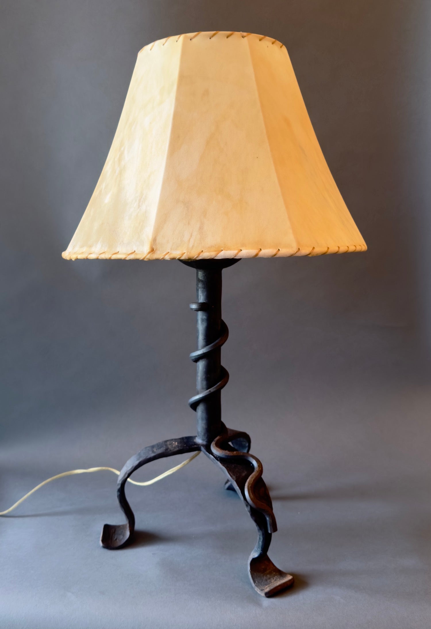 Wrought iron lamp with a forged steel vine wrapped around the stem. Shown with a handmade sheepskin shade.