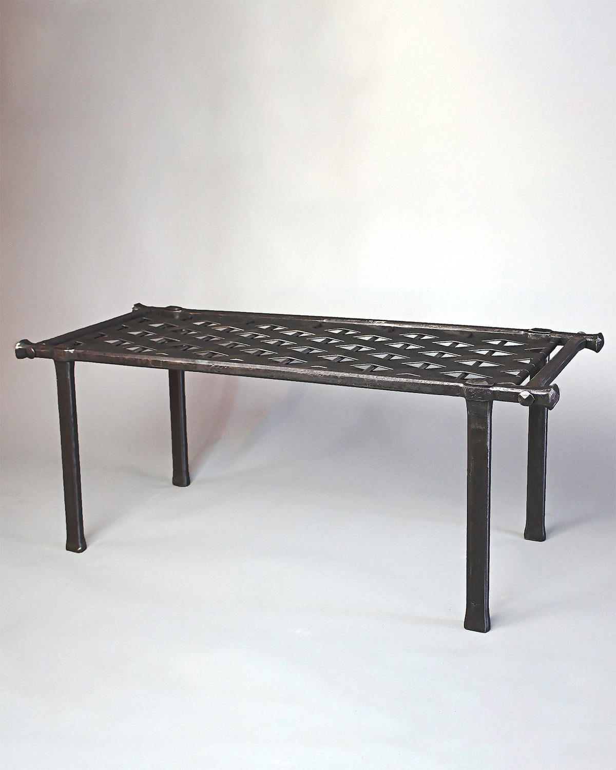 Handcrafted woven wrought iron bench by artisan blacksmith Christopher Thomson. This decorative ironwork bench features intricate woven metalwork and a durable, artistic design, perfect for indoor or outdoor use in luxury spaces. An elegant blend of traditional blacksmith techniques and modern metal forging craftsmanship.