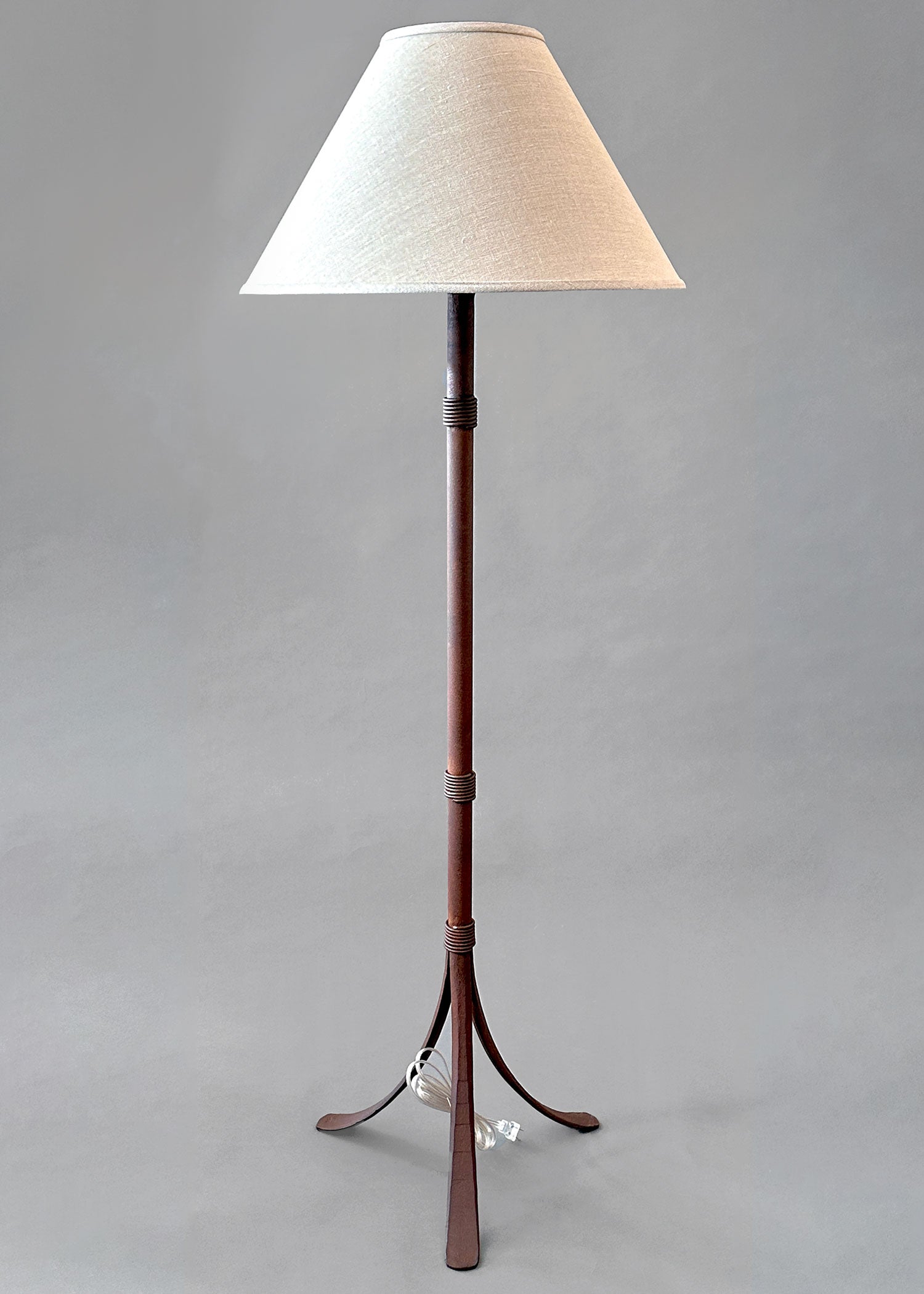 Rustic wrought iron floor lamp made from hand forged steel and paired with a woven linen shade.