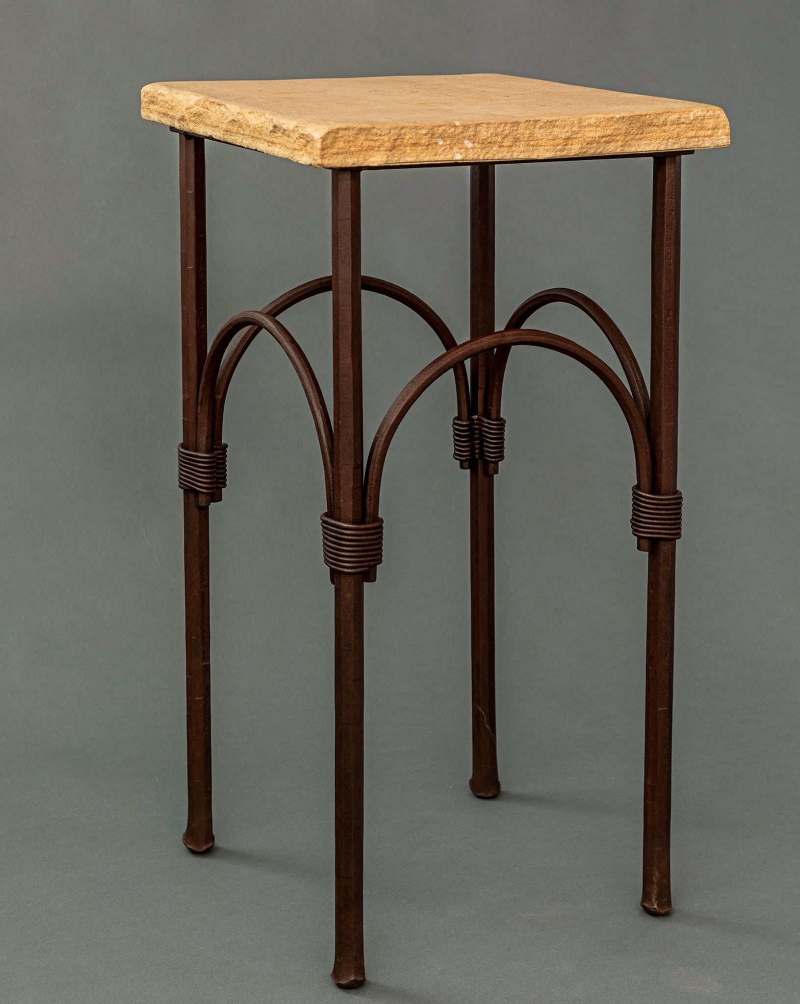 A naturally rust finished forged steel pedestal table with a flagstone top.