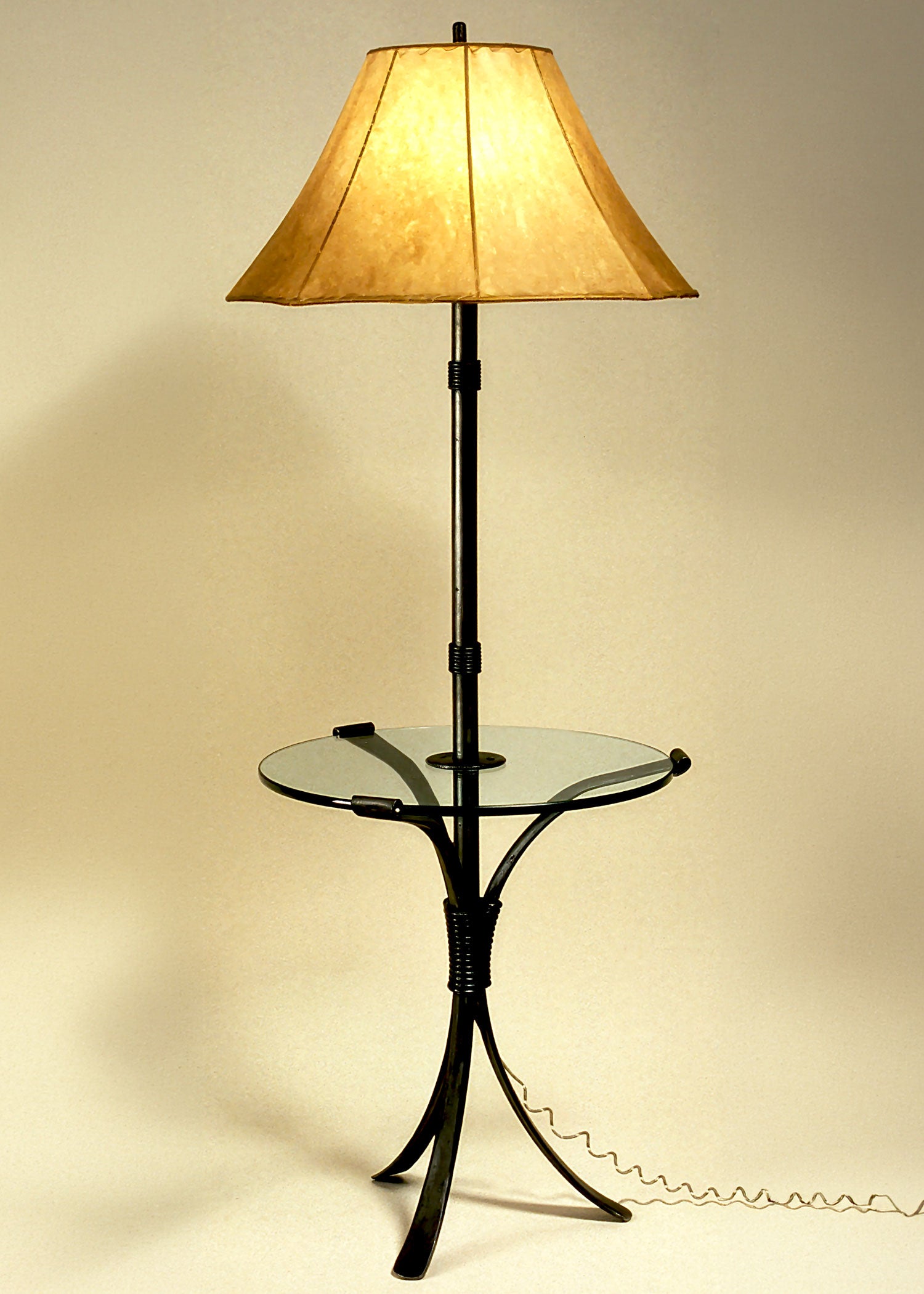 Wrought Iron Lamp Table shown with a raw hide sheepskin shade. The floor lamp extends out of the center of the table, serving as a table/lamp combo. 
