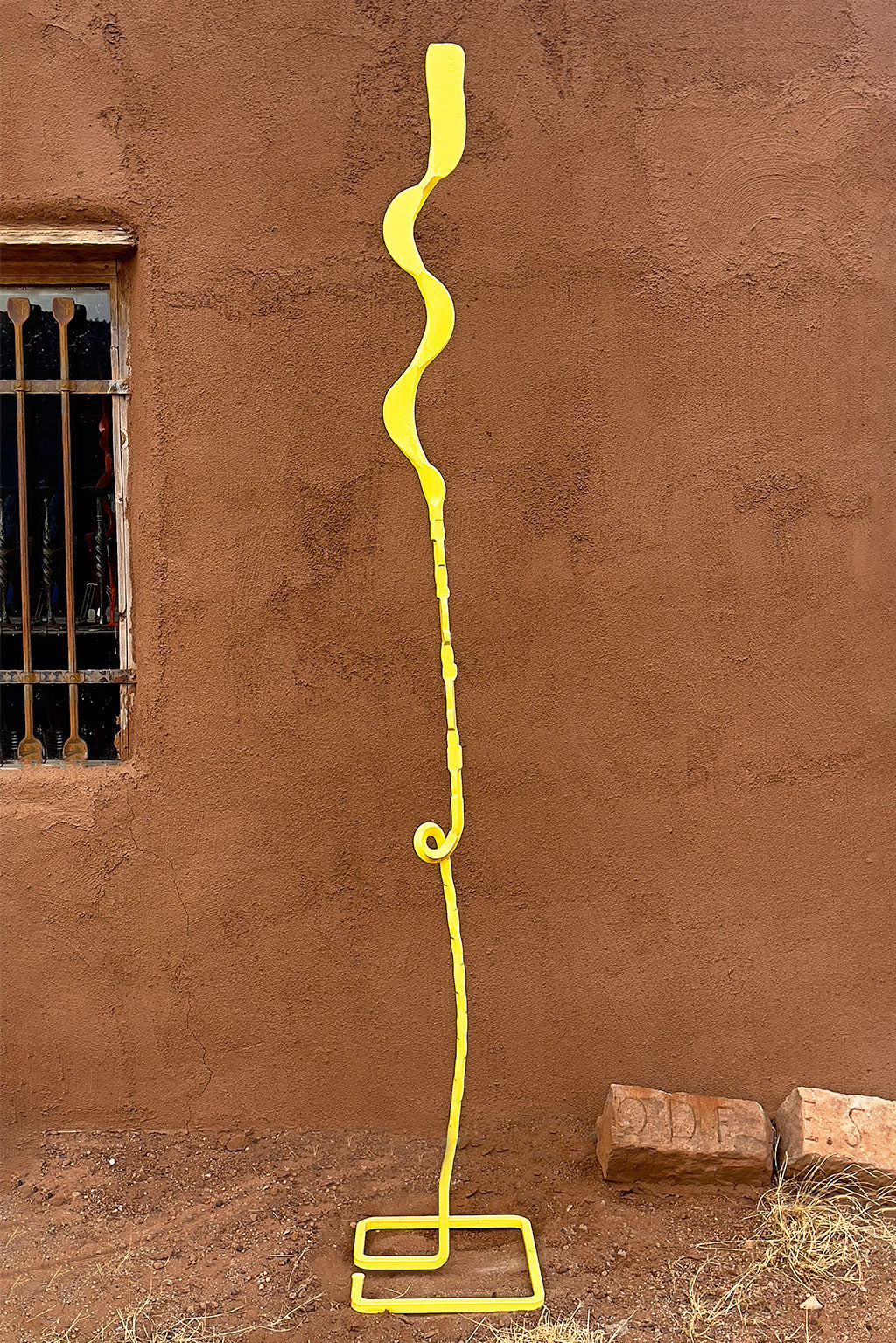 Pineapple Yellow Free Standing Single Bloom sculpture against an adobe wall. 