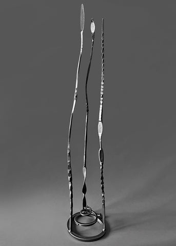 Metallic charcoal colored forged steel "Baby Pajos" free standing sculpture with three long tendrils pointing up.