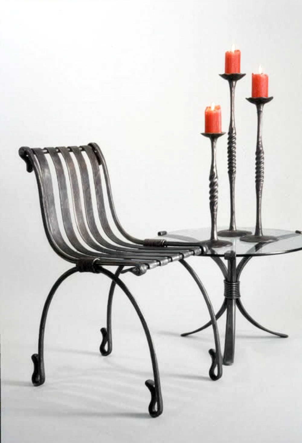 Wrought candle holders, on a forged steel table next to hand forged chair by award winning blacksmith from Santa Fe, New Mexico, Christopher Thomson. 