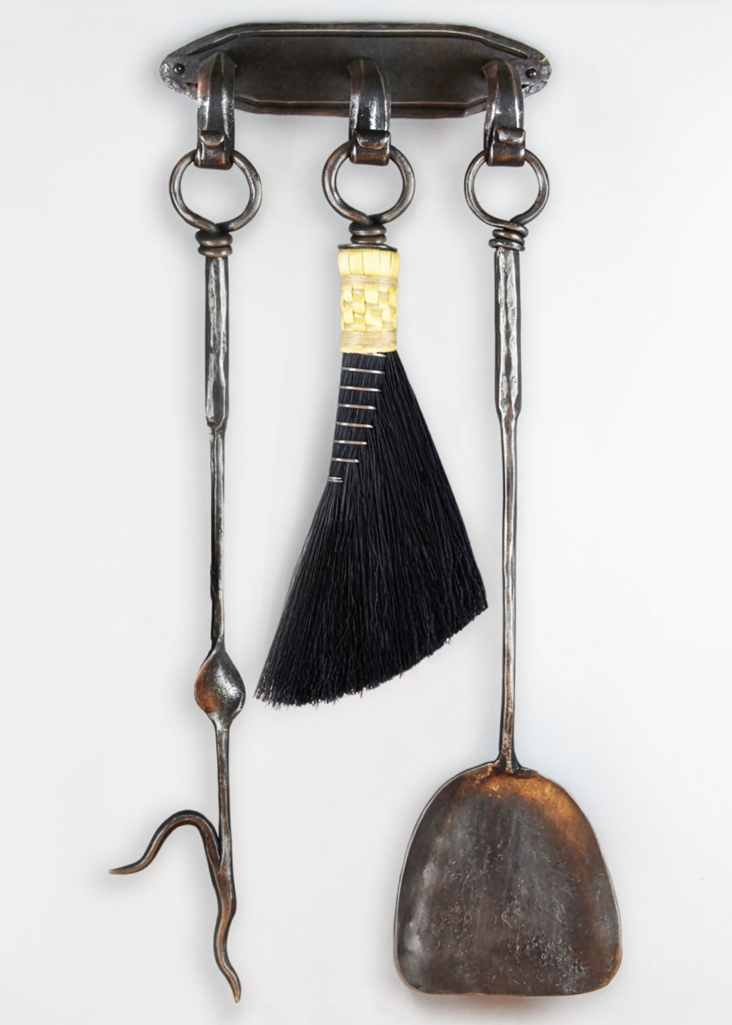 Wrought iron wall mounted fireplace tool set with a hand forged fire poker, broom and shovel. 